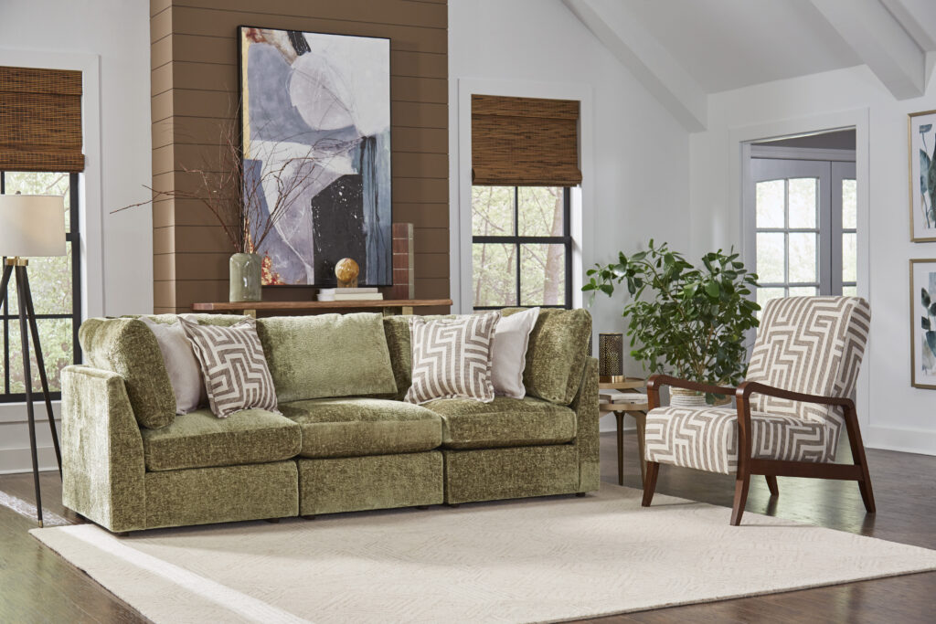 Best Home Furnishings Green upholstered stationary sofa with three cushions and square arms, styled with patterned accent pillows in a bright living room.