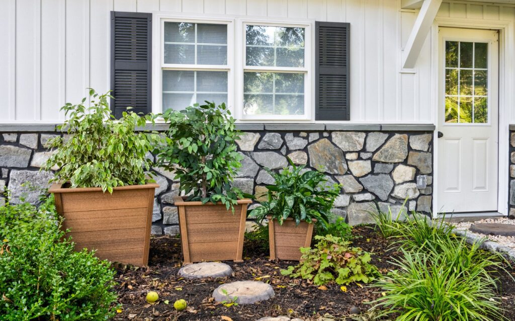 Poly planters and raised garden beds in front of a stone wall